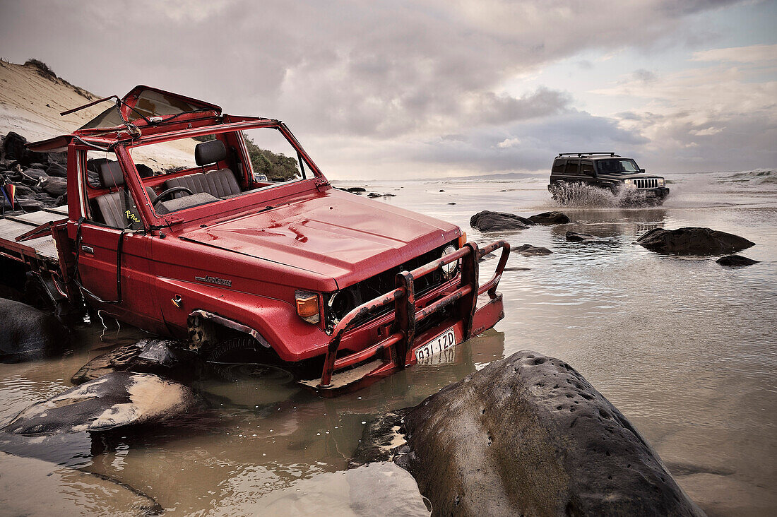 Stranded offroad vehicle at Rainbow Beach, water crossing at high tide, Queensland, Australia