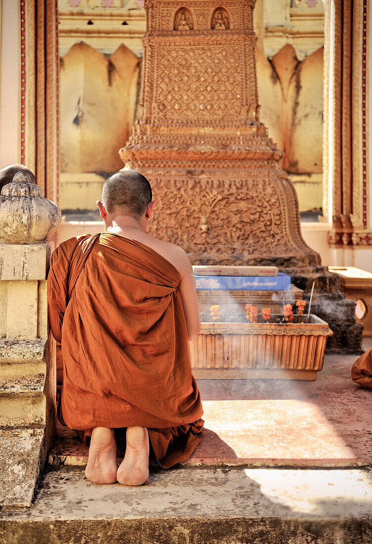 Buddhistischer Mönch beim Gebet im Tempel Pha That Luang, Vientiane, Laos