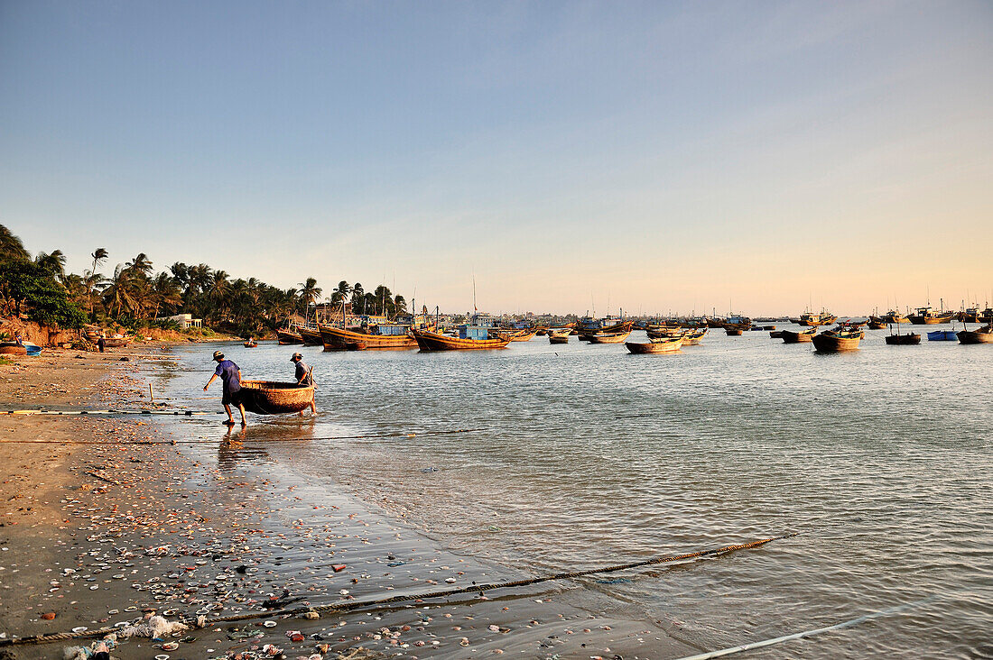 Fischer tragen ihr kleines Boot an den Strand , Fischerboote, Fischerdorf, Südchinesisches Meer, Mui Ne, Binh Thuan, Vietnam