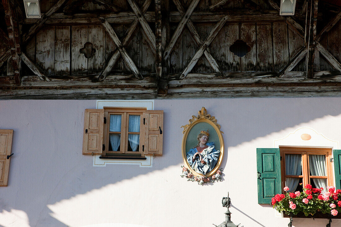 Traditional exterior wall with geraniums and depiction of a holy person, Mittenwald, Bavaria, Germany
