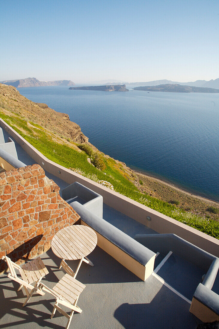 Wooden table and chairs on roof terrace by sea, Santorini