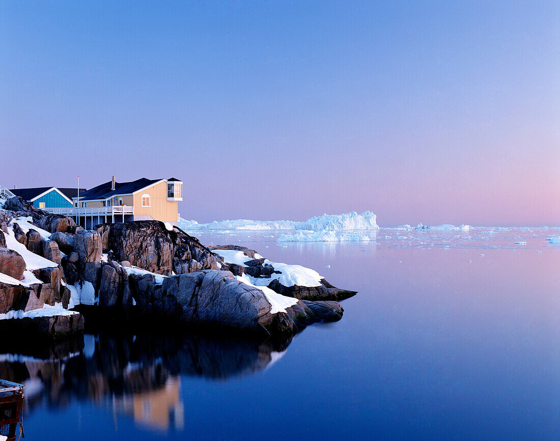 Houses on the coastline with icebergs, Disko Bay, Greenland