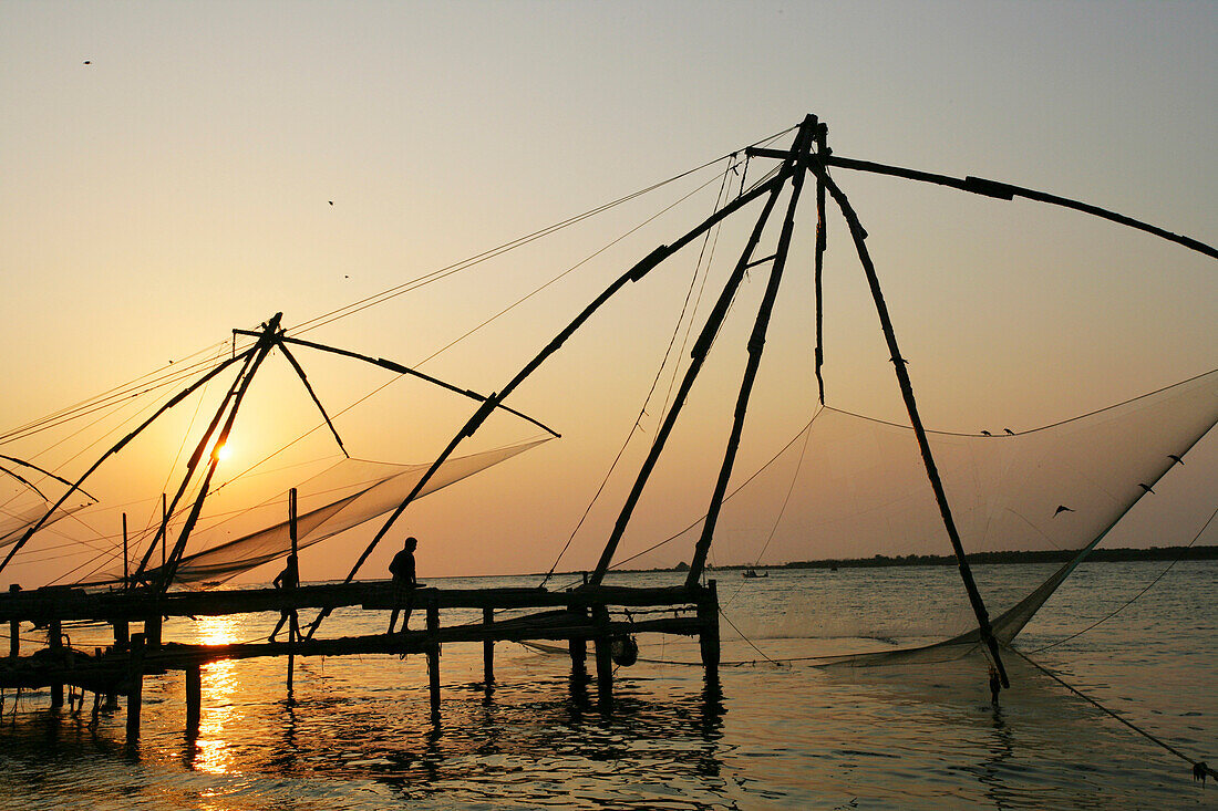 Chinese fishing nets hanging in the water at sunset, Fort Kochi, Cheena valas (Chinese fishing nets) at Fort Kochi (Fort Cochion), Kerala, India.