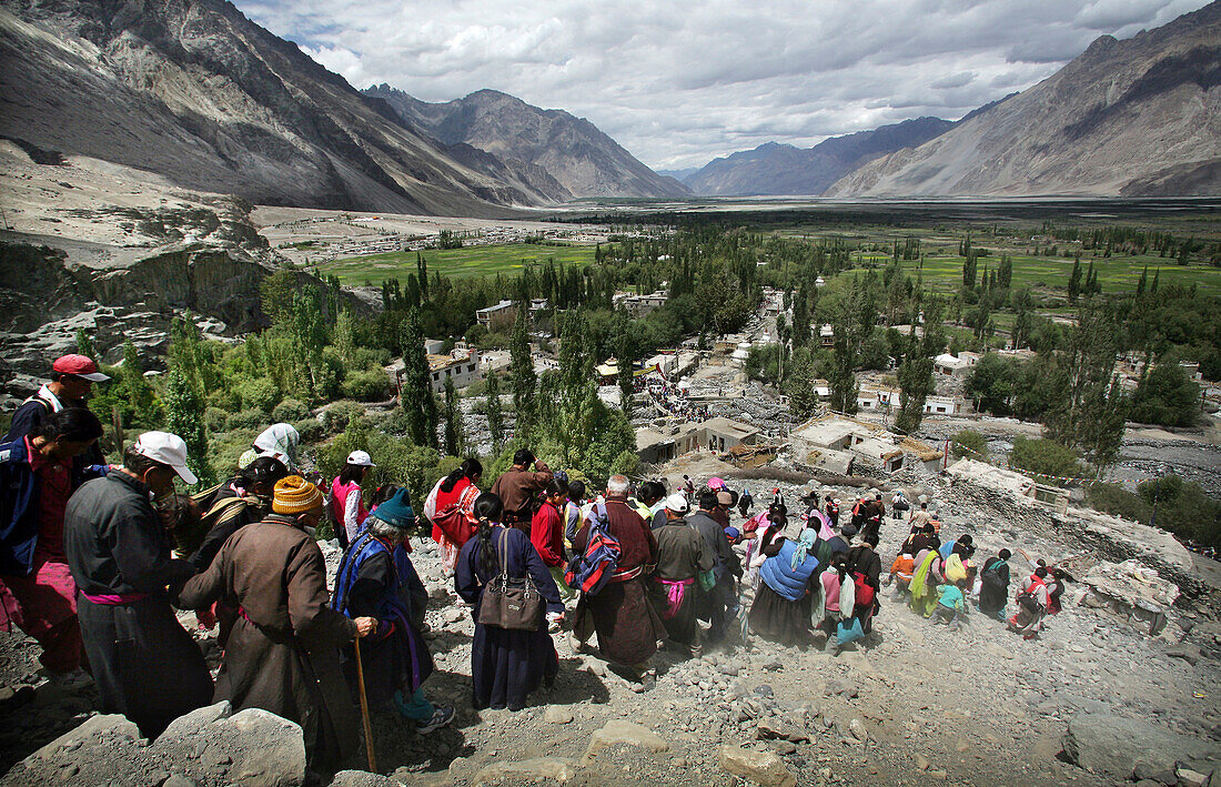 Ladakhi people and Buddhist monks walking down the mountain in a line, Nubra Valley, Leh Ladakh, India
