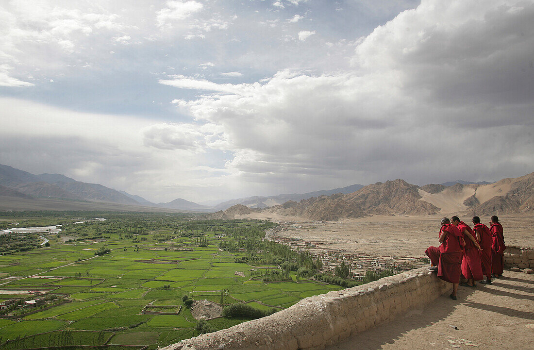 Buddhist monks on rooftop at Thikse Monastery looking over Indus Valley, Gompa, near Leh, Ladakh, India