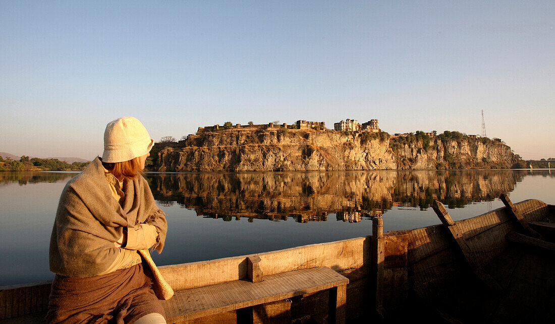 Woman sitting on fence looking at Bhainsrorgarh Fort, Rajasthan, India