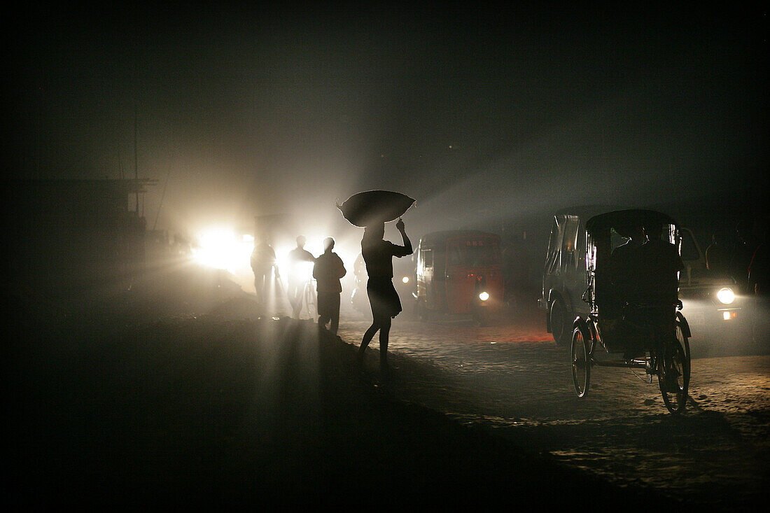 Silhouettes of traffic and people carrying sacks on their heads at night, Agartala, Tripura, North East States, India