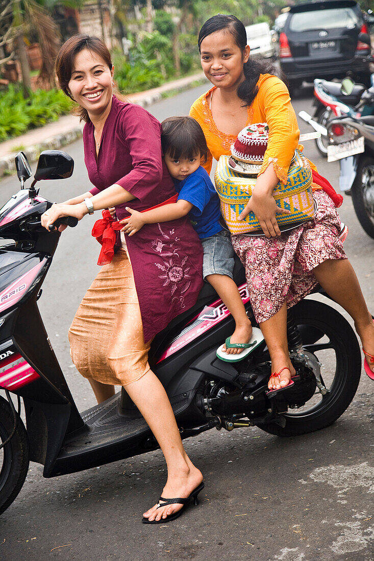 Two women and boy sitting on motorbike, Ubud, Bali, Indonesia