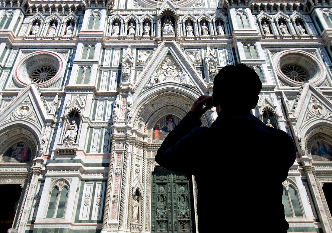Silhouette of woman taking photograph of the facade of the Duomo, Florence, Tuscany, Italy