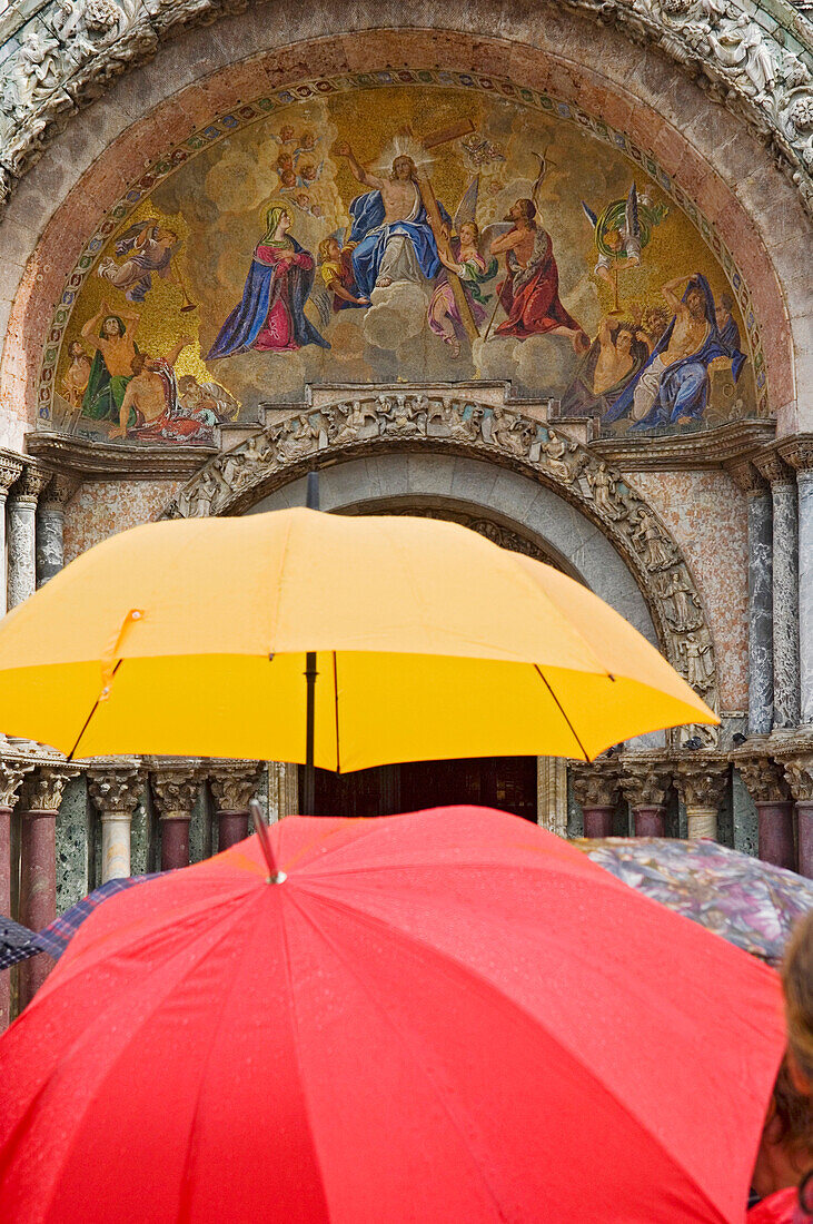 Tourists in the rain in Venice, Saint Mark's Basilica (Basilica San Marco), Venice, Italy.