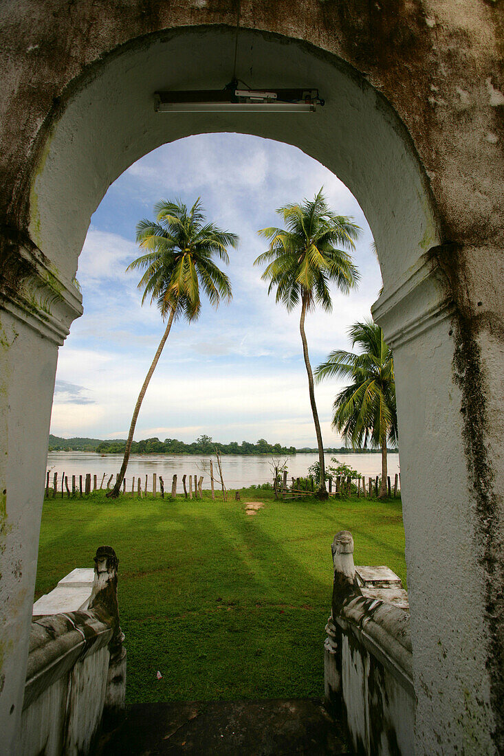View through archway towards Mekong river and palm trees, Don Khong Island, Champasak Province, Si Phan Don Islands