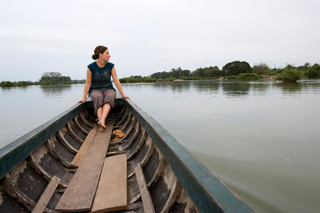 Young woman traveller on boat trip amongst the 4000 islands of Si Phan Don, Mekong river, Laos.
