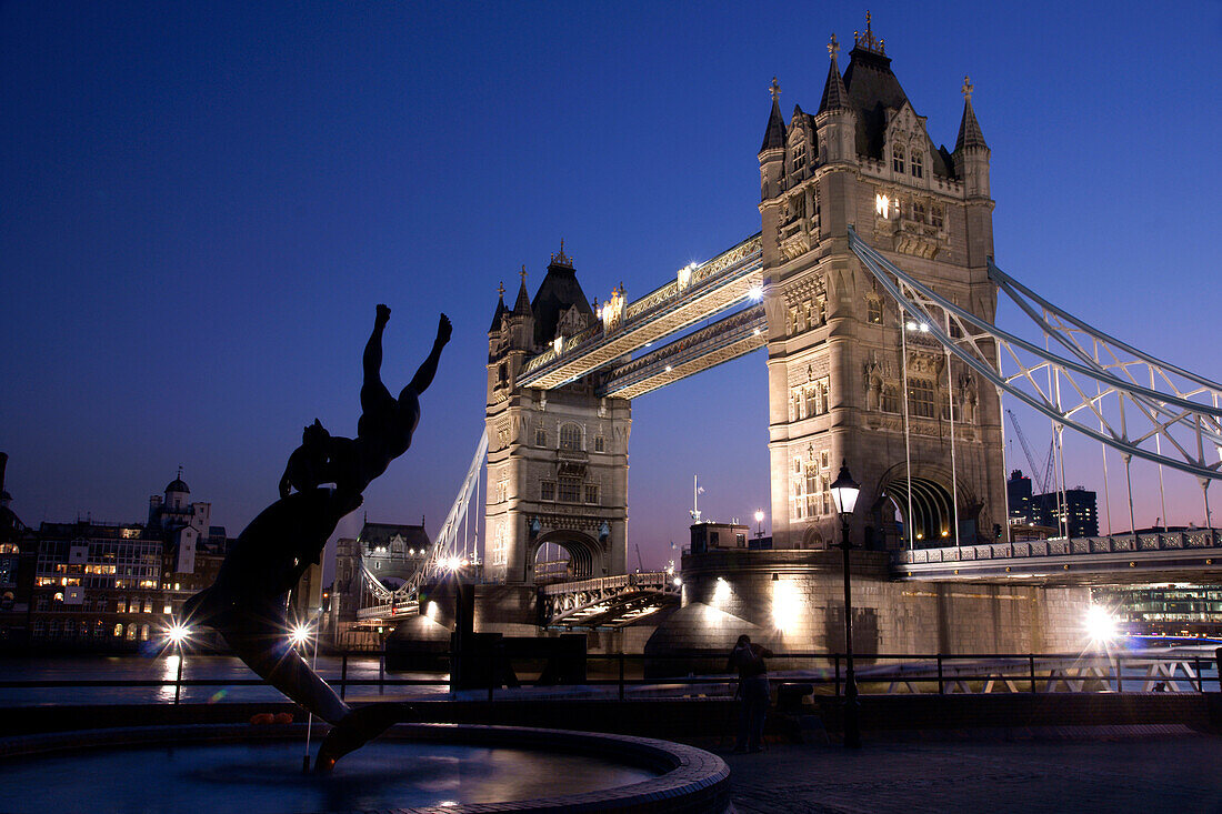 Tower Bridge at dusk with dolphin statue in the foreground, London, England, UK