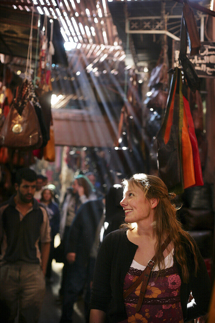 A woman browsing clothes and handbags in the souk, Shopping in the Medina, Marrakech, Morocco.