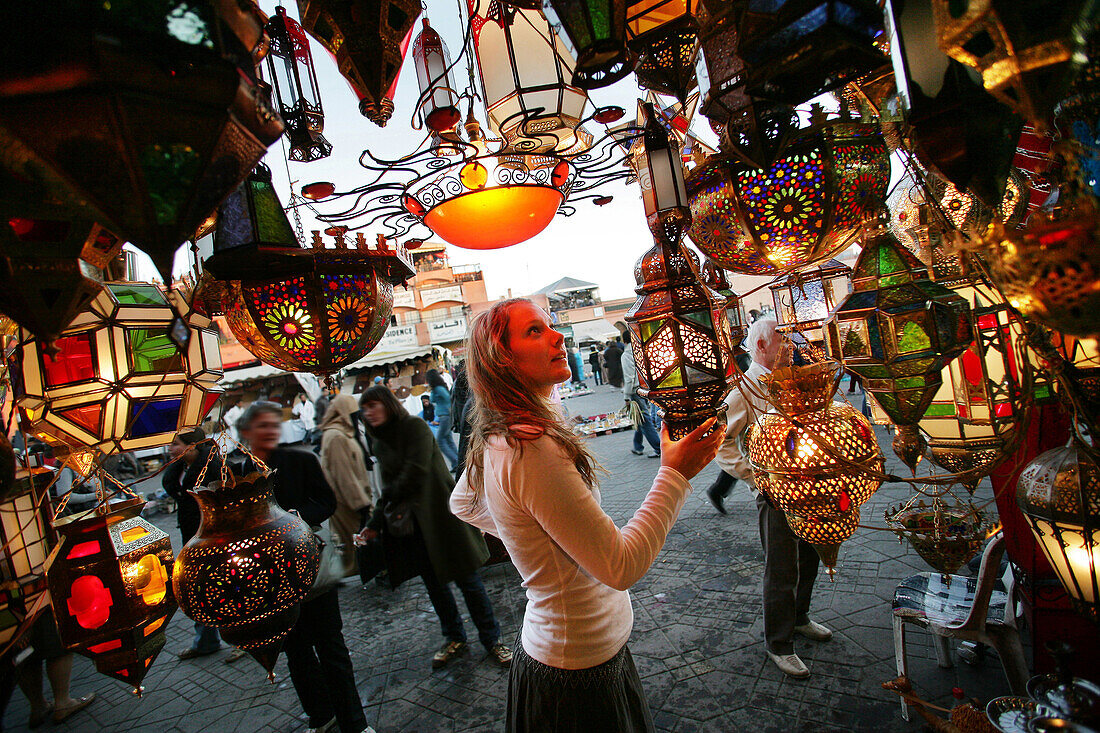 A woman browsing for Moroccan lanterns in a market stall in the souk, Shopping in the Medina, Marrakesh, Morocco.