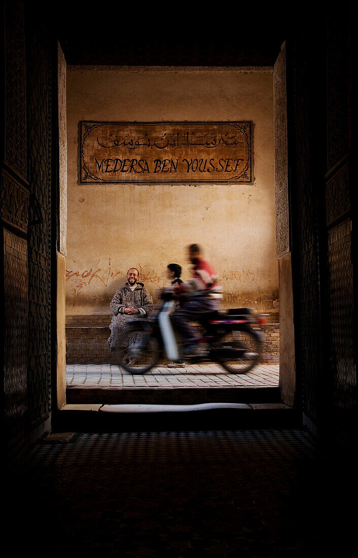 Motorbike passing entrance of Ali Ben Youssef Medersa, Marrakesh, Morocco