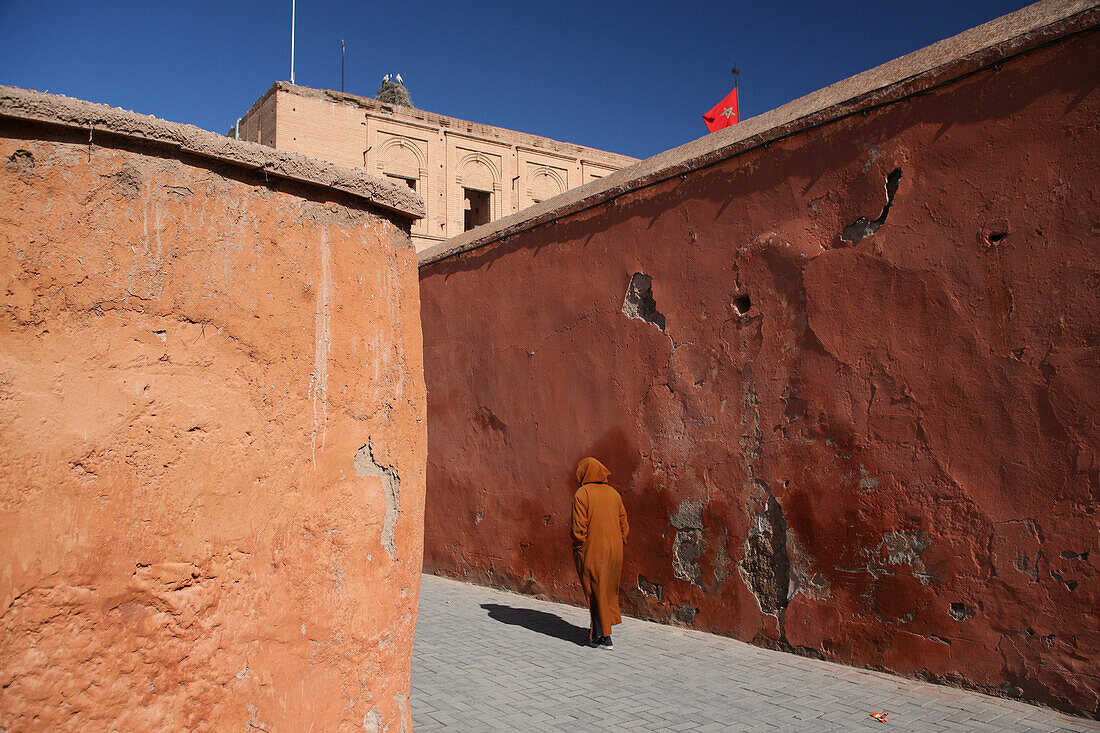 Local man wearing long-hooded cloak known as a djellaba, worn by both male and females, blends into the colourful walls near the Royal Palace in Marrakesh/Marrakech, Morocco, Marrakesh/Marrakech, Morocco.
