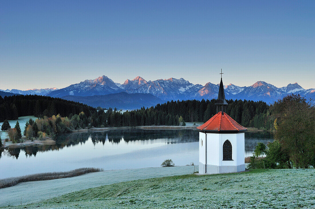 Chapel and lake with view of Tannheimer range at sunrise, lake Forggensee, Allgaeu, Allgaeu range, Swabia, Bavaria, Germany, Europe