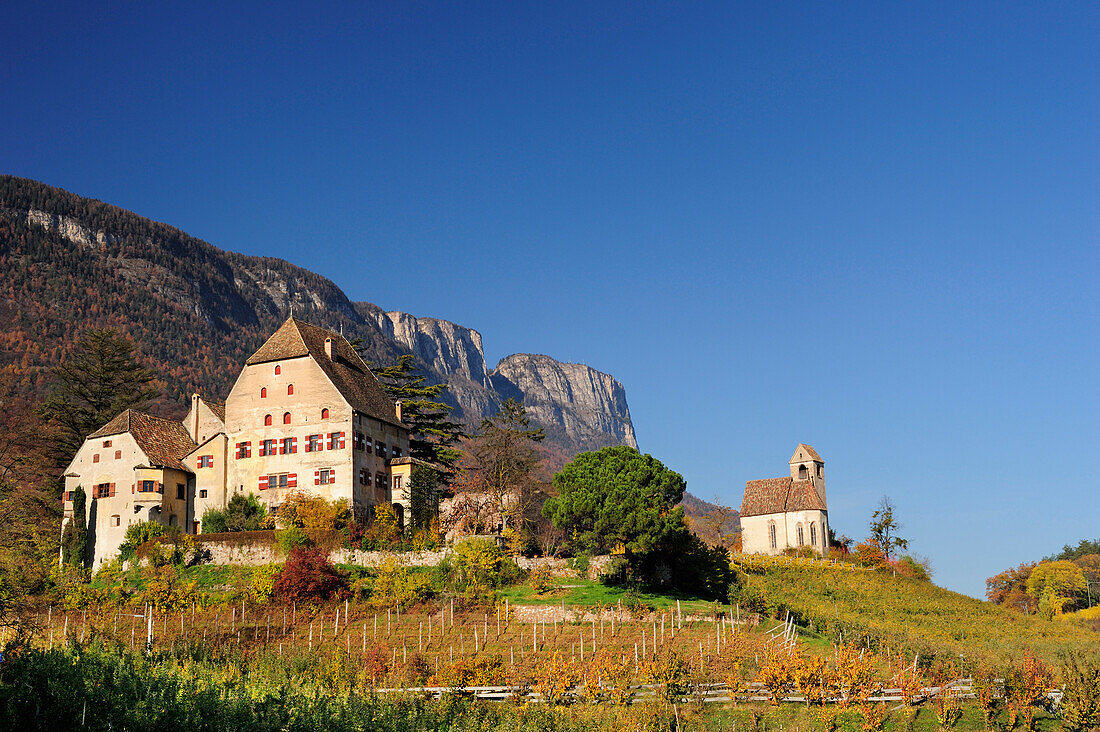 Gutshof und Kirche in herbstlich verfärbten Weinbergen mit Felswand im Hintergrund, nahe Kalterer See, Südtirol, Italien, Europa