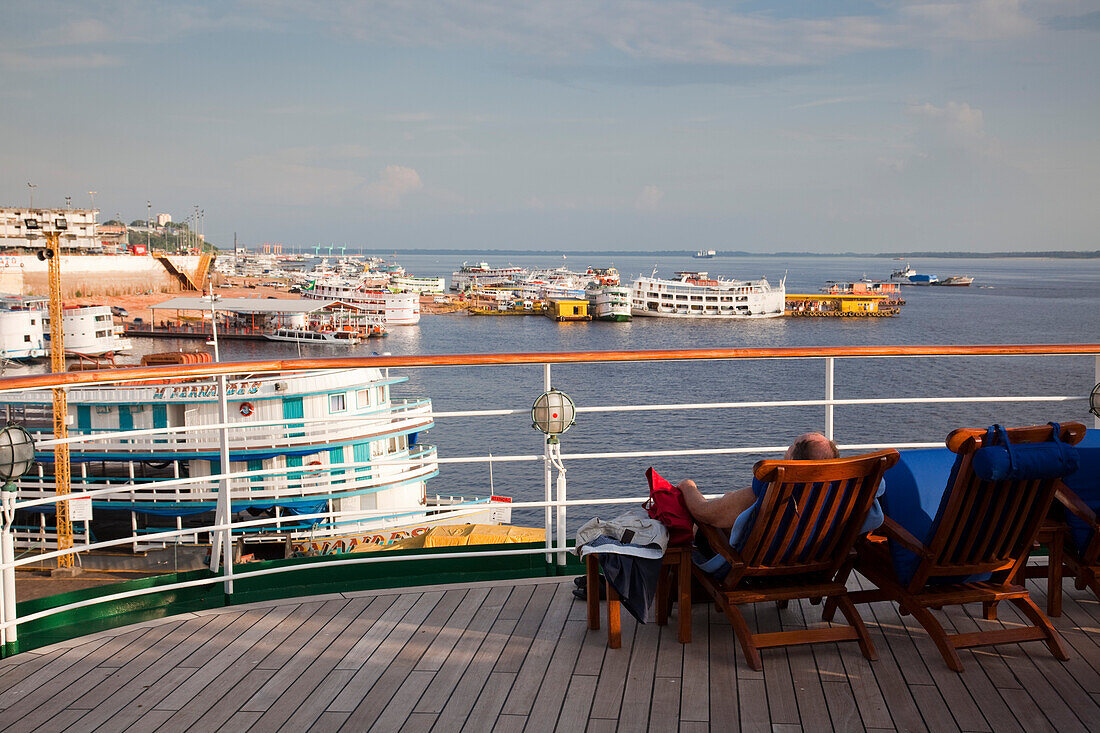 Gäste sitzen an Deck von Kreuzfahrtschiff MS Deutschland, Reederei Peter Deilmann, und blicken auf Amazonas Flussdampfer, Manaus, Amazonas, Brasilien, Südamerika