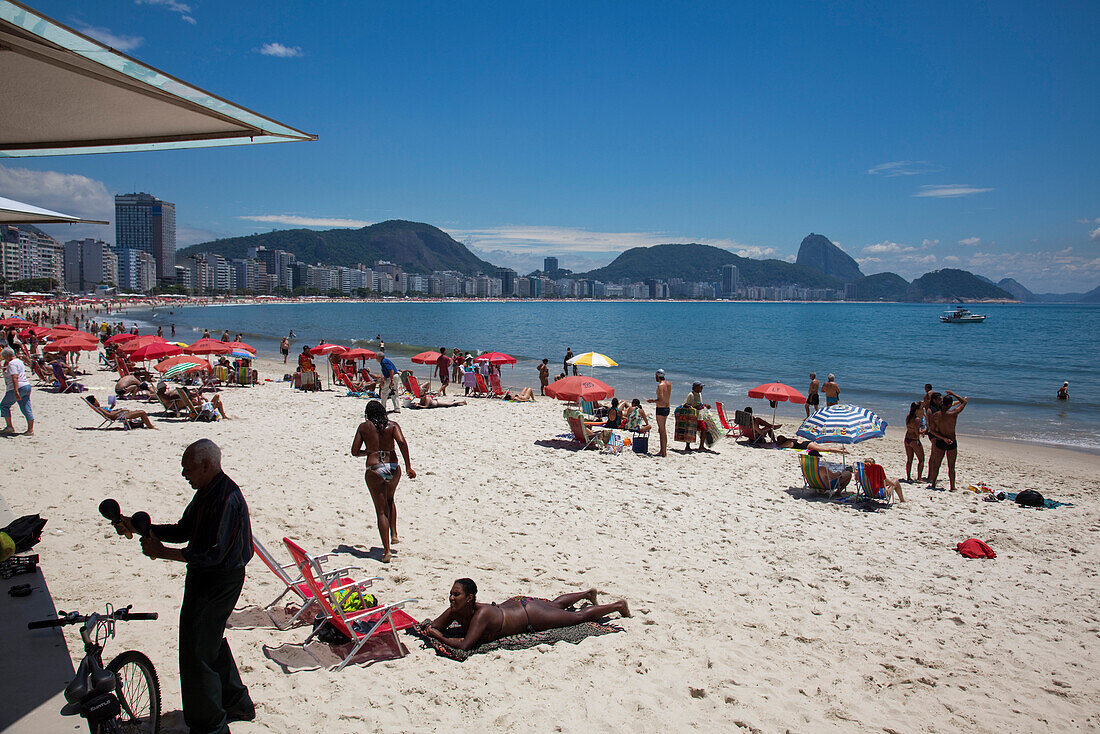 Menschen am Strand der Copacabana mit Zuckerhut in der Distanz, Rio de Janeiro, Rio de Janeiro, Brasilien, Südamerika