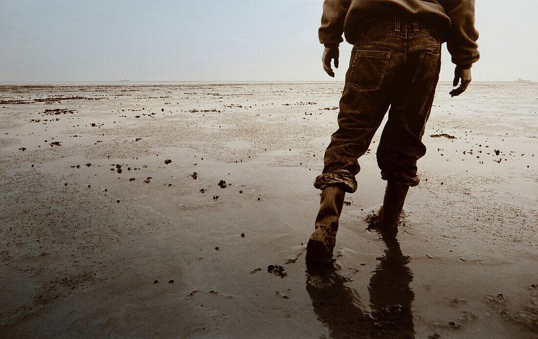Man with rubber boots, mudflat hiking tour, East Frisian Wadden Sea, East Friesland, North Sea, Lower Saxony, Germany, Europe