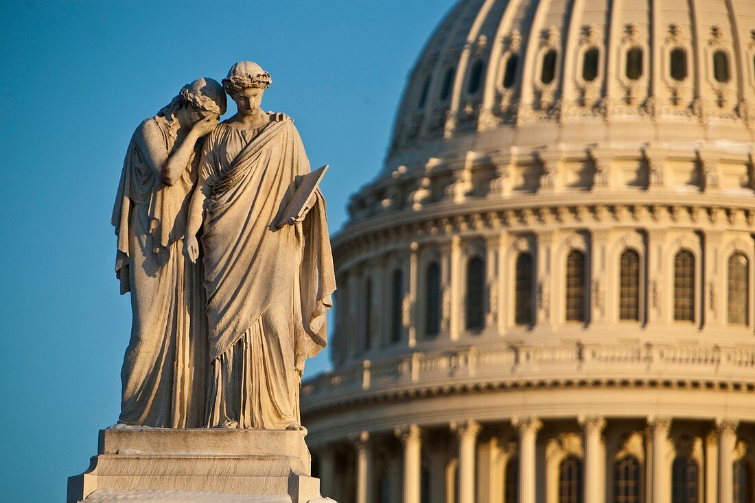 Two marble statutes of women in front of Capitol Dome