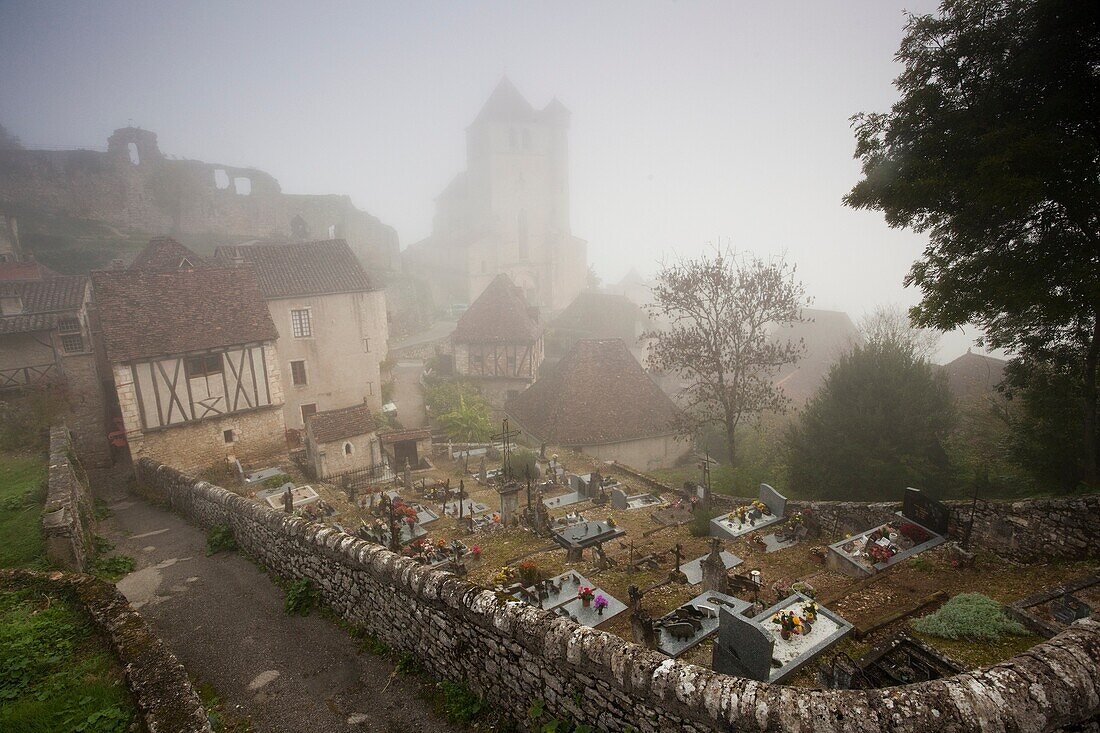 France, Midi-Pyrenees Region, Lot Department, St-Cirq-Lapopie, town overview in fog with 15th century church