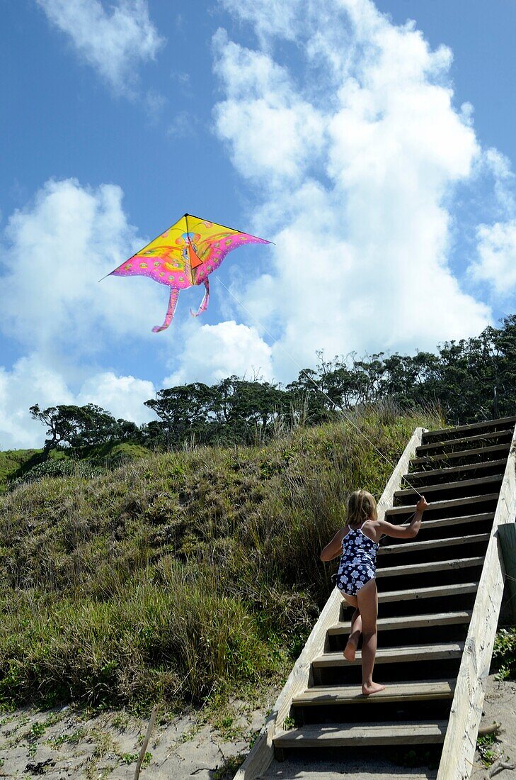 Six year old girl flying a kite at the beach  Mimiwhangata, Northland, New Zealand