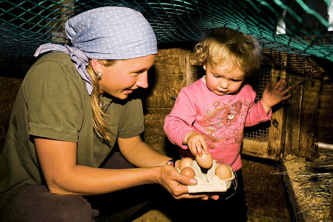 Frau und Mädchen sammeln Eier ein, Hofbauern-Alm, Kampenwand, Chiemgau, Oberbayern, Bayern, Deutschland