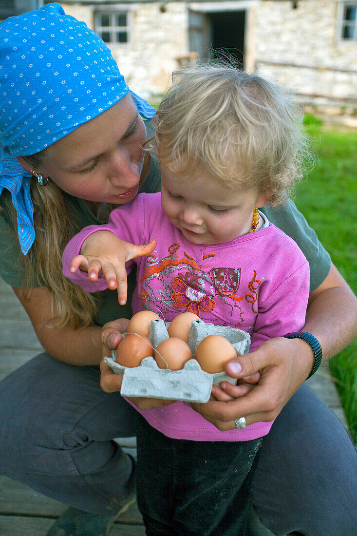 Woman and girl with fresh eggs, Hofbauern-Alm, Kampenwand, Chiemgau, Upper Bavaria, Germany