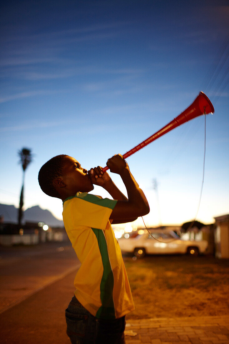 Junge spielt Vuvuzela im Guguletu Township am Abend, Cape Flats, Kapstadt, Südafrika, Afrika