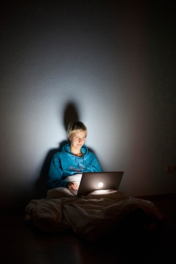 Frau sitzt auf Boden in einer leeren Wohnung, schaut in Laptop, Notebook, Apple Macbook, Arbeit am Computer, MR, Leipzig, Sachsen, Deutschland