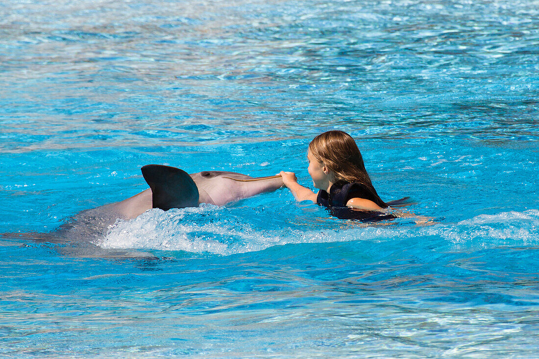 Mädchen spielt mit Delfin in Delfinarium, Portugal, Europa