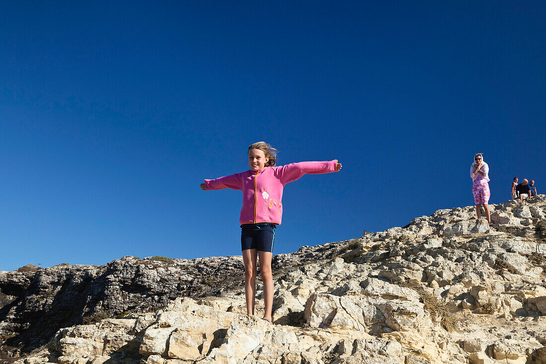 Mädchen stellt sich gegen den Wind auf den Klippen des Cabo de Sao Vicente, Algarve, Portugal, Europa