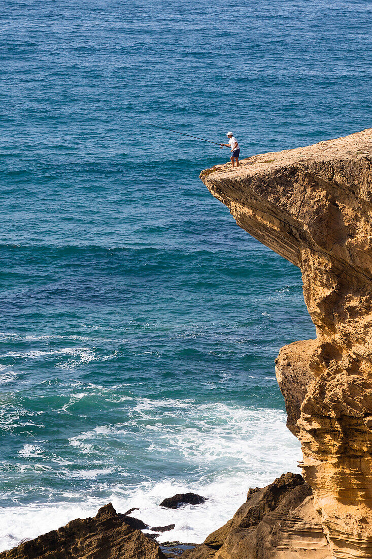 Fisherman on cliff at Monte Clerigo Beach, Atlantic Coast, Algarve, Portugal, Europe