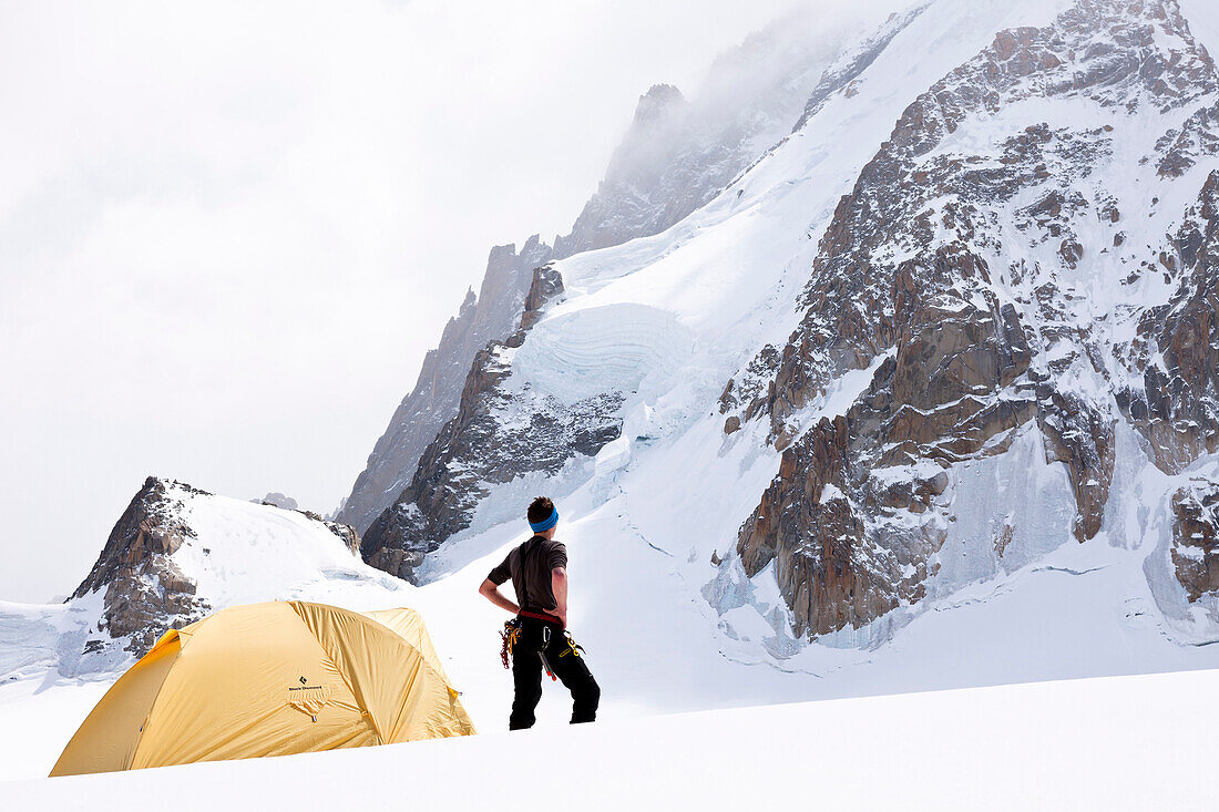 Mountaineer in front of a tent under Mont Blanc du Tacul, Chamonix, Mont-Blanc, France