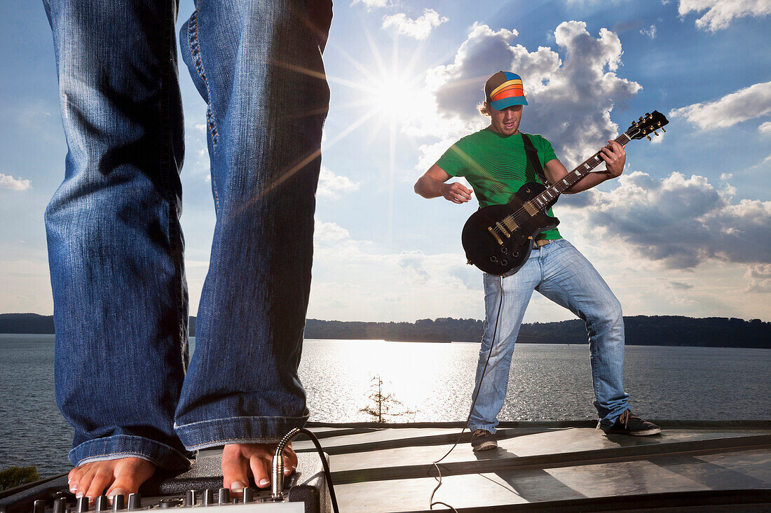 Guitarist above Lake Starnberg, girl standing barefoot on amplifier, Upper Bavaria, Germany