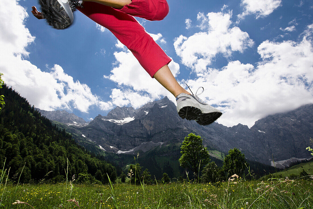 Junge Frau in roter Jogginghose springt auf Wiese, Eng, Ahornboden, Karwendel Gebirge, Tirol, Österreich, Europa
