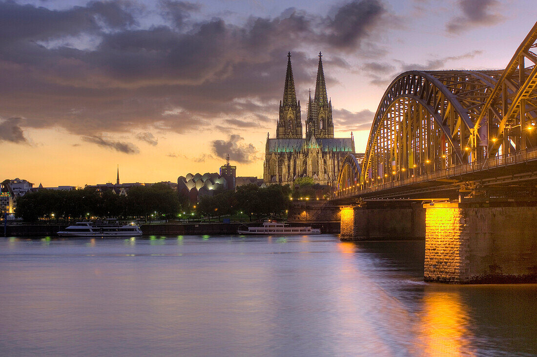 View over Rhine river in the evening light to Cologne Cathedral and Hohenzollern Bridge, Cologne, North Rhine-Westphalia, Germany