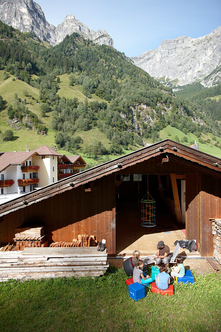 Kinder sitzen vor einer Hütte und schnitzen, Hotel Feuerstein, Gossensaß, Brenner, Südtirol, Trentino-Südtirol, Italien