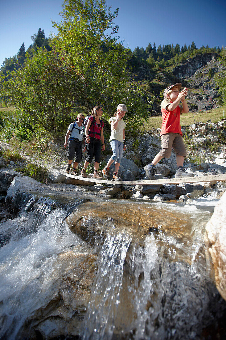 Family crossing a stream, family hike,  Pflersch, Gossensass, South Tyrol, Italy