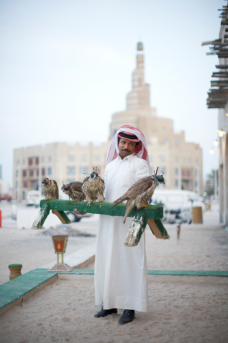 Bird Center salesman with falcons, Islamic Cultural Centre in background, Doha, Qatar