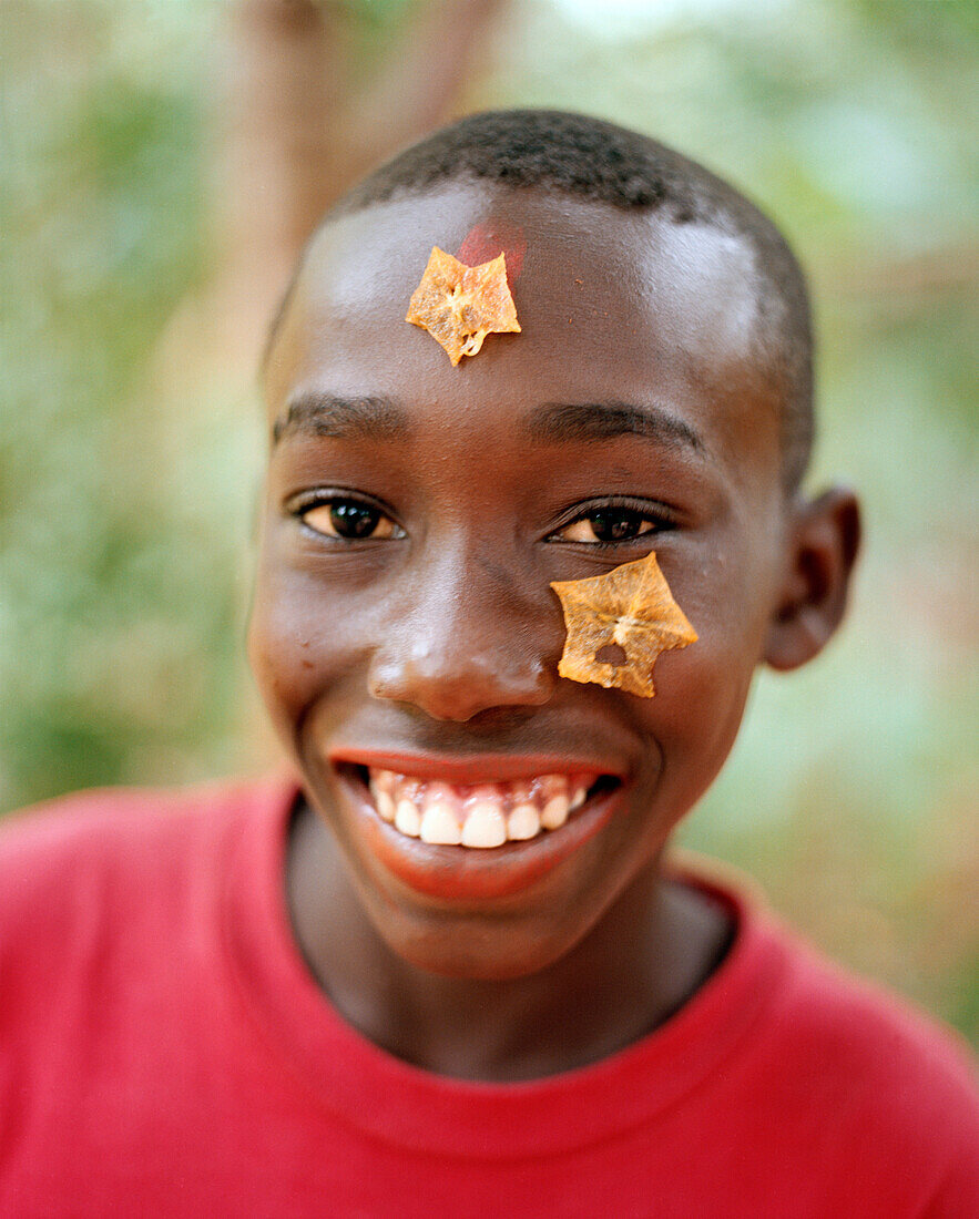 Boy with carambola on his forehead during a Spice Tour on Hakuna Matata Spice Farm, Dole village near Kidichi, north east of Zanzibar Town, Zanzibar, Tanzania, East Africa
