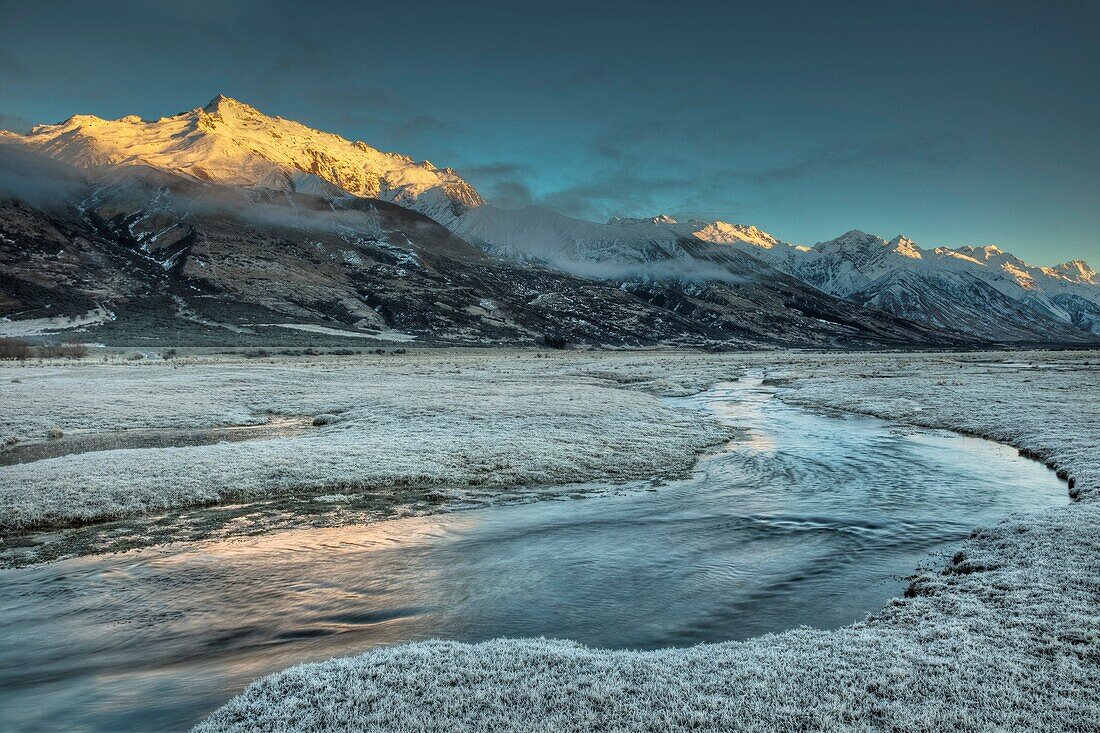 Dawn light on Ben Ohau range near Glentanner Station, frosted grass on Tasman river flats, edge of Aoraki / Mt Cook National park, New Zealand