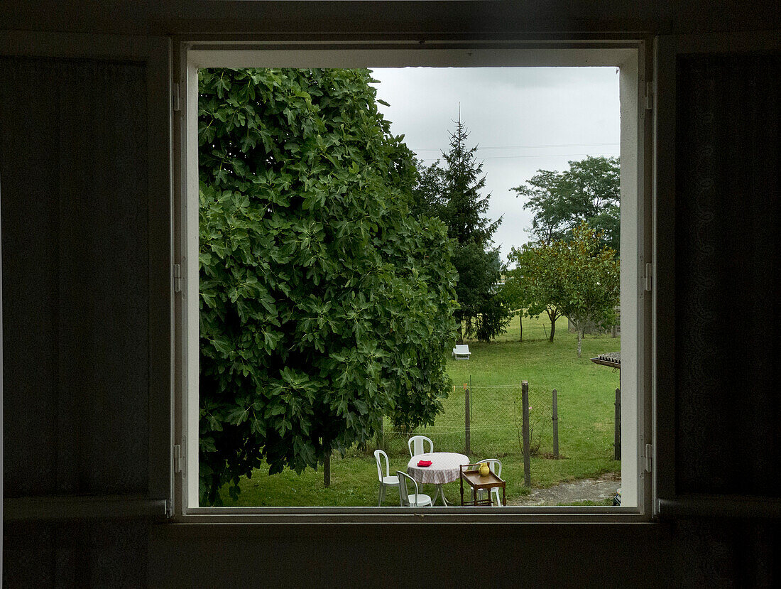 Table and Chairs in Backyard Viewed Through Window, Arancou, Pays Basque, France