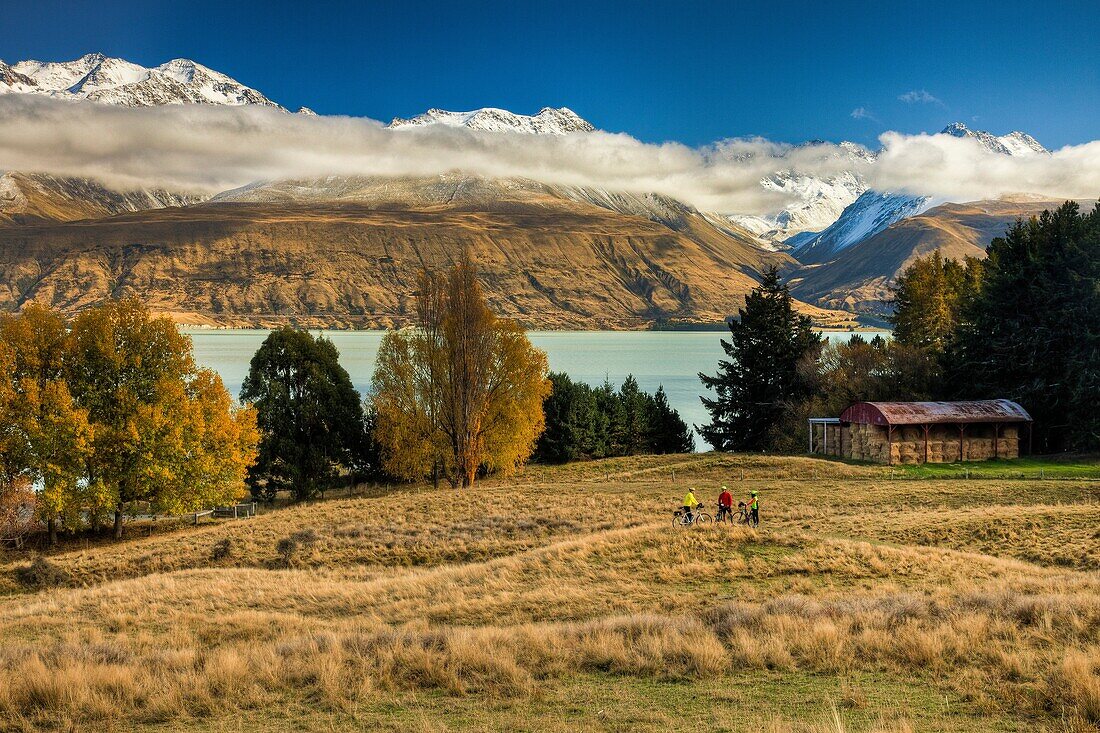 Cyclists near Braemar station barn, landscape of Lake Pukaki and Ben Ohau Range, Mackenzie country, Canterbury