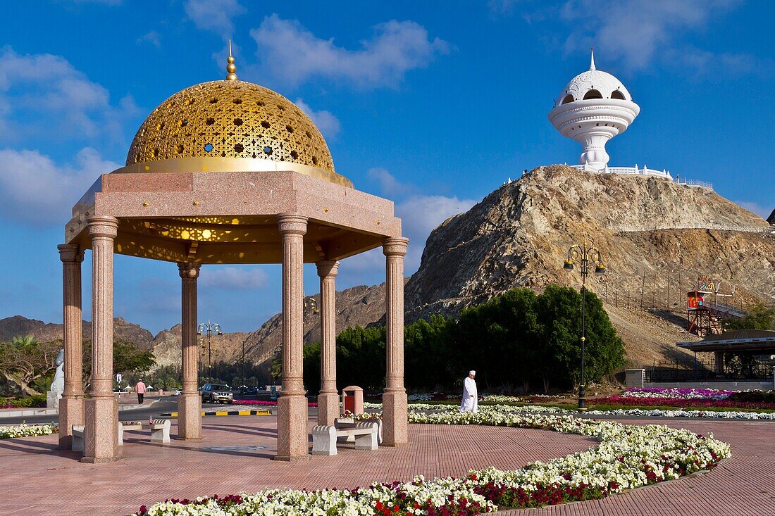 A gold dome cupola shelter and the incense burner landmark overlooking the Corniche promenade in Muscat, Oman