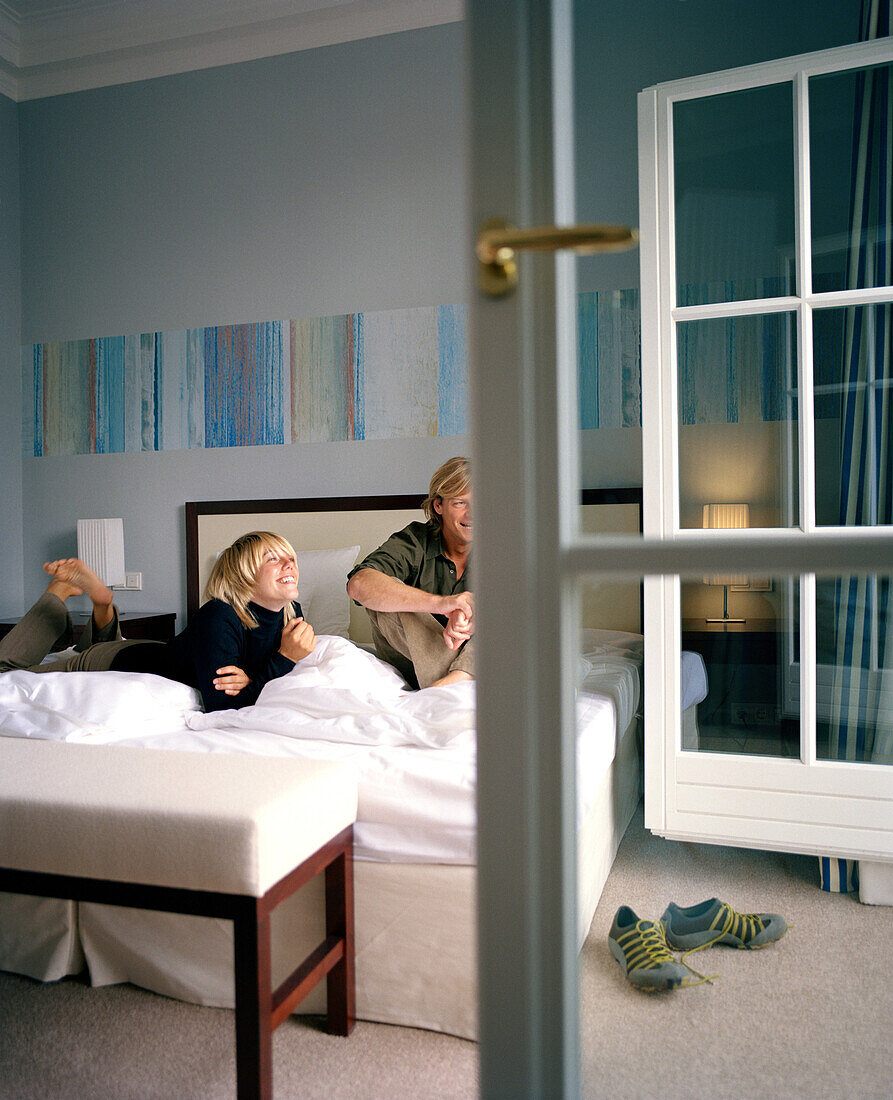 Couple on a double bed in a hotel room, spa resort, Travemuende, Luebeck, Schleswig-Holstein, Germany