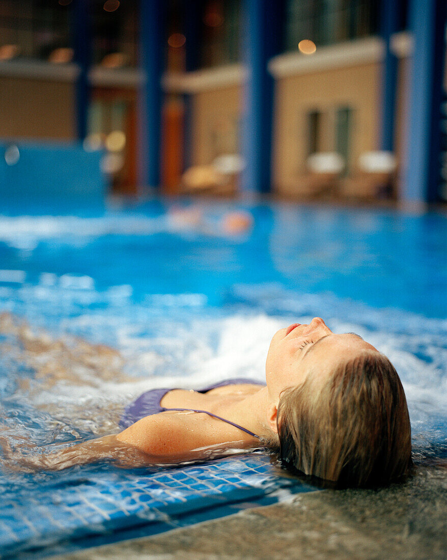 Woman lying in a swimming pool in a spa resort, Travemuende, Luebeck, Schleswig-Holstein, Germany